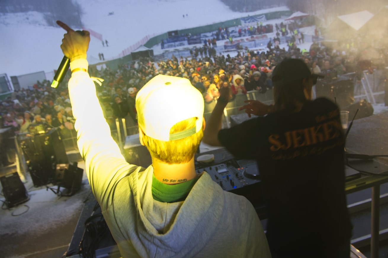 DJ med mikrofon foran et stort publikum på et vinterarrangement
